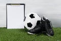 Soccer ball and shoes on the grass on a light background, a place for your inscription