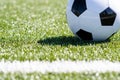 Soccer ball sitting in grass close to line