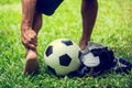Soccer ball and sport shoes on green grass with soccer player catch the ankle of the feet because of pain Royalty Free Stock Photo