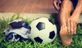 Soccer ball and sport shoes on green grass with soccer player in foot  pain Royalty Free Stock Photo