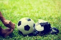 Soccer ball and sport shoes on green grass with soccer player in foot  pain Royalty Free Stock Photo