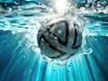 Soccer ball is submerged in water. The ball is surrounded by blue and green colors, which create an aquatic environment