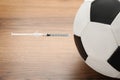 Soccer ball with syringe on wooden table, closeup. Doping concept Royalty Free Stock Photo