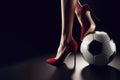 A soccer ball on which stands a female foot with a red heel close up on solid black background. ai generative Royalty Free Stock Photo