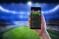 Soccer betting online app on smart phone ih man hand with football stadium