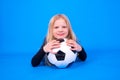 Soccer fans. Cute blonde girl in black shirt holding soccer ball in hands over blue studio background. Copyspace Royalty Free Stock Photo