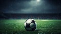 A soccer field with green grass, soccer ball lying on the field, rain coming down