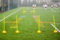 Soccer field with training equipment and fence in background. Junior football team training with coach in the background