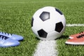 Soccer football background. Soccer ball and two pair of football sports shoes on artificial turf soccer field Royalty Free Stock Photo