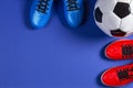 Soccer football background. Top view of soccer ball and two pair of soccer football sports shoes on blue background Royalty Free Stock Photo