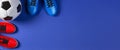 Soccer football background. Top view of soccer ball and two pair of soccer football sports shoes on blue background Royalty Free Stock Photo