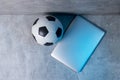 Soccer and football ball and grey laptop on grey background. Online workout concept