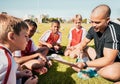 Soccer, football coach with team talk and strategy with tactics winning game sitting on grass training field. Boy Royalty Free Stock Photo
