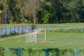 Soccer goal in a lush green field, with two blue uprights standing tall in the background