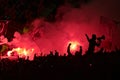 Soccer hooligans fans with smoke bombs and flags.