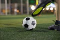 Soccer player foot kicking ball on football field