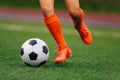 The soccer player hits the ball on the artificial turf. Footballer in sports cleats kicking a ball