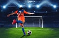 Soccer scene at night match with player in an orange and blue uniform kicking the penalty kick Royalty Free Stock Photo