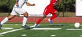 Soccer player in red uniform dribbling the ball with player in white uniform chasing Royalty Free Stock Photo