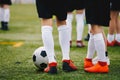 Soccer players with ball on a training field. Young junior level athletes in football cleats and uniforms on grass training ground