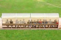 Soccer players and staff sit on bench beside the soccer field.