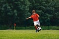 Soccer shooting. Boy kicking soccer ball on grass field. Young football player in action running jumping, and shooting the ball Royalty Free Stock Photo