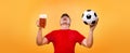 Soccer sports fan - happy man at oktoberfest, taking beer and soccer ball on yellow background. Royalty Free Stock Photo