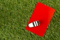 Soccer sports referee red card with whistle on grass background - penalty, foul or sports concept, top view flat lay from above Royalty Free Stock Photo