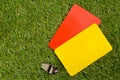 Soccer sports referee yellow and red cards with chrome whistle on grass background flat lay from above Royalty Free Stock Photo