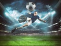 Soccer striker hits the ball with an acrobatic kick in the air at the stadium at night match Royalty Free Stock Photo