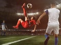 Soccer striker in red uniform hits the ball with an acrobatic kick in the air at the stadium Royalty Free Stock Photo