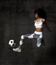 Soccer woman player jumps and hit the ball strike in the middle on concrete loft wall Royalty Free Stock Photo