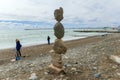 SOCHI,RUSSIA,  18 APRIL 2019 - pyramid of stones on the Black sea shore and people walking on the beach in cloudy weather Royalty Free Stock Photo