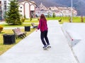 Sochi, Russia - 26 December 2019. A girl in a plaid shirt rides a skateboard on a concrete sidewalk in a resort town