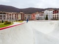 Sochi, Russia - 26 December 2019. A gray concrete skatepark with a guy riding in the distance on rollers located in a