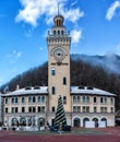 Sochi, Russia - December 24, 2018: The main building in the Rosa Khutor town hall clock tower, surrounding by woods and mountains