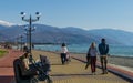 People resting on sunny winter day on Olympic Embankment in Sirius against Caucasus mountains Royalty Free Stock Photo