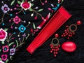 SOCHI, RUSSIA DECEMBER 10, 2019: A red fan, earrings and a musical shaker lie on a black Spanish flamenco shawl Royalty Free Stock Photo