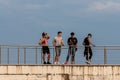 Group of four young males standing against blue sky background