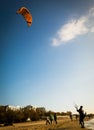 Kite- surfers have finished flying and are folding their wing kites on sandy beach