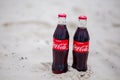 Sochi, RUSSIA - November 23, 2019: two glass classic bottles of Coca-Cola on white sand beach