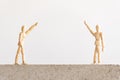 Social distancing symbol: two wooden human figures standing on a concrete block with a good separation between them, waving