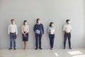 Job seekers in face masks waiting for job interview standing in corridor keeping safe distance Royalty Free Stock Photo