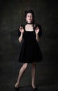Portrait of young beautiful woman in image of medieval royal person in black dress isolated on dark vintage background.