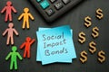 Social impact bonds sign, calculator and figurines. Royalty Free Stock Photo