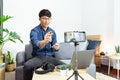 Social media influencer or blogger present and review recording or streaming vlog about product using smartphone on tripod for