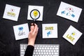 Social media promotion. Work desk with socail media icons. Black background top view. Hand with magnifier