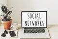 social networks text on laptop screen on wooden desktop with phone, notebook, coffee and plant. business workspace. global Royalty Free Stock Photo