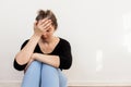 social problems, depression and loneliness.a young upset woman is sitting against the wall, holding her head with her hand. Royalty Free Stock Photo