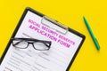 Social security benefits. Application form near pen and glasses on yellow background top view Royalty Free Stock Photo